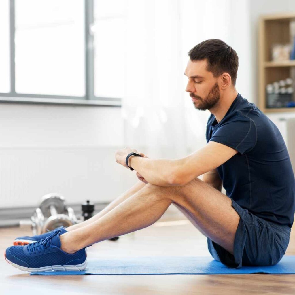 Man on exercise mat looking at smartwatch